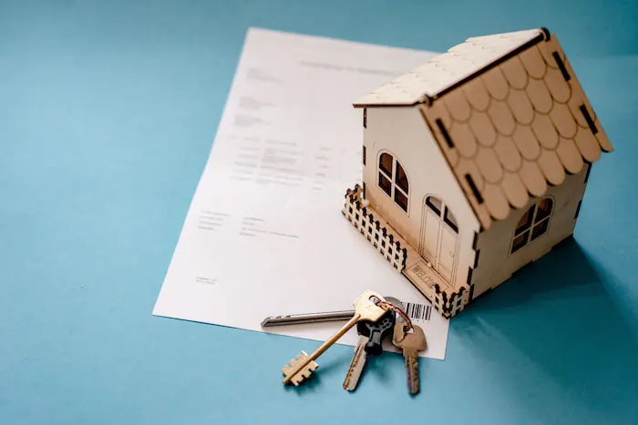 Petite maison en bois posée sur contrat avec clés à côté, reflet d’une désolidarisation d’un prêt immobilier et séparation des engagements financiers.