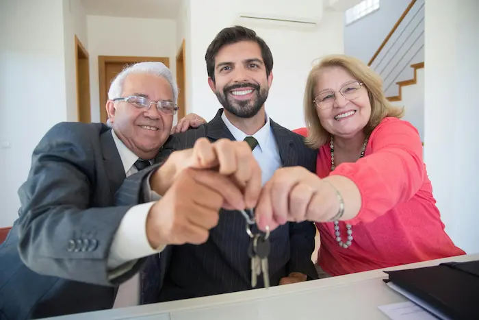 Trois personnes souriantes tenant des clés reflétant la création d’une SCI dans le cadre d’un héritage.