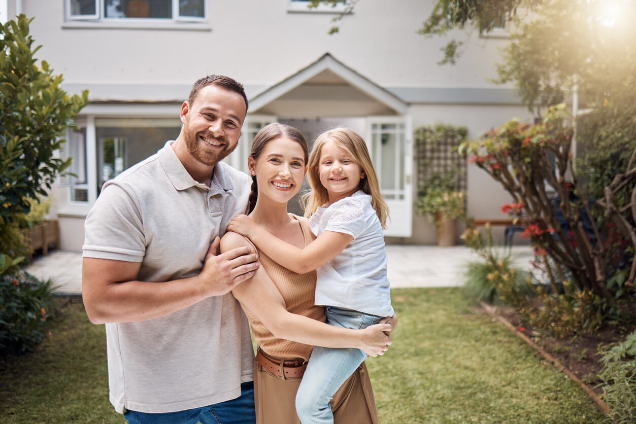 Une famille souriante posant devant leur maison, symbole d'un projet réussi de rachat immobilier en SCI. Une démarche idéale pour optimiser la gestion et la transmission de leur patrimoine familial.