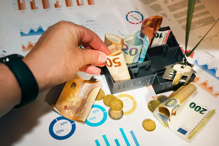 Main tenant un billet de cinquante euros reflétant la vigilance et la discipline nécessaires pour calculer les revenus locatifs.
