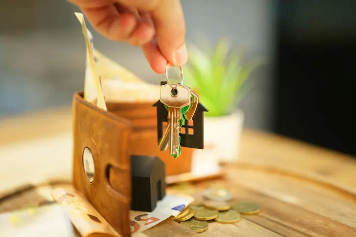 Main tenant trousseau de clés avec maison, image illustrant le remboursement anticipé d’un crédit immobilier pour alléger les mensualités.