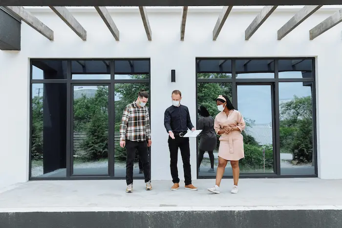 Trois personnes discutant devant immeuble moderne, image illustrant l’achat d’une SCI