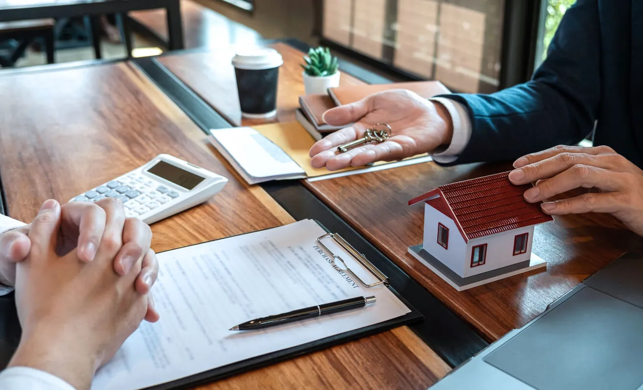 Deux personnes échangent un contrat, symbolisant la signature d’un bail locatif. Agence immobilière gestion locative Bayonne assure une gestion sécurisée des biens