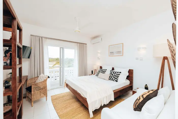 Chambre moderne lumineuse avec lit en bois et balcon illustrant l’attrait d’un achat d’appartement neuf 