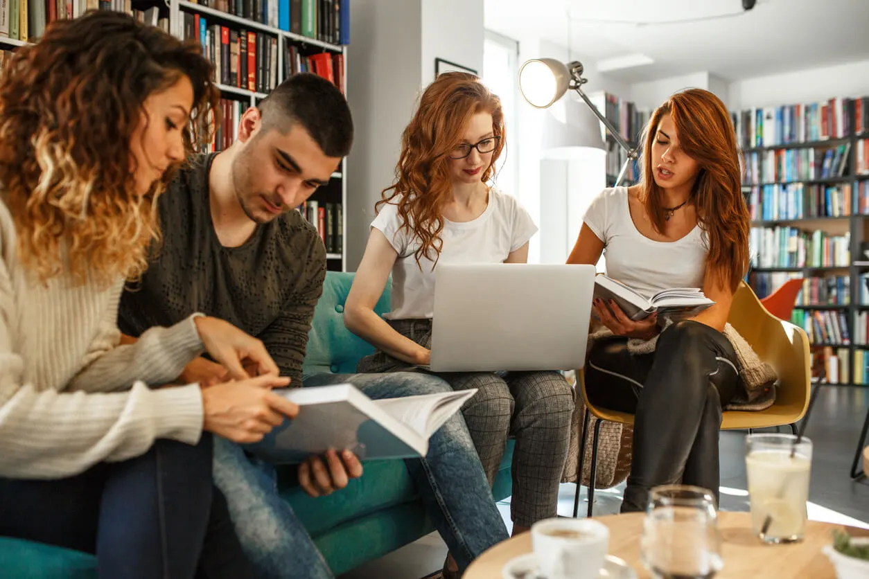 Des étudiants plongés dans leurs livres et ordinateurs dans une bibliothèque lumineuse. Pendant que certains révisent, d’autres échangent sur leurs projets futurs. En arrière-plan, une discussion porte sur l’opportunité d’acheter une résidence étudiante, un investissement prisé pour répondre à la forte demande de logements universitaires