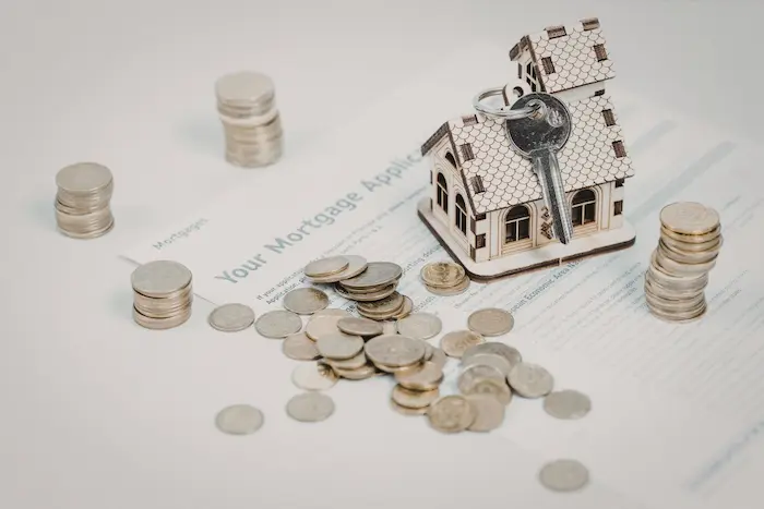 Maquette de maison posée sur un dossier de prêt, pièces et clé illustrant le calcul du taux d’intérêt pour un prêt immobilier