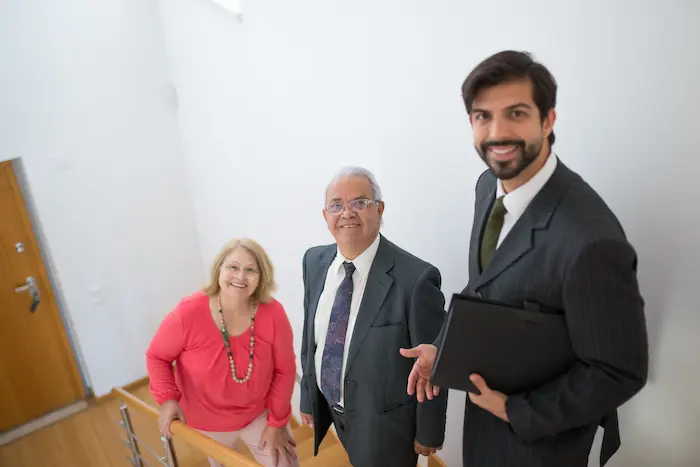 Trois personnes en tenue professionnelle discutant sur escalier moderne, symbole des démarches pour investir