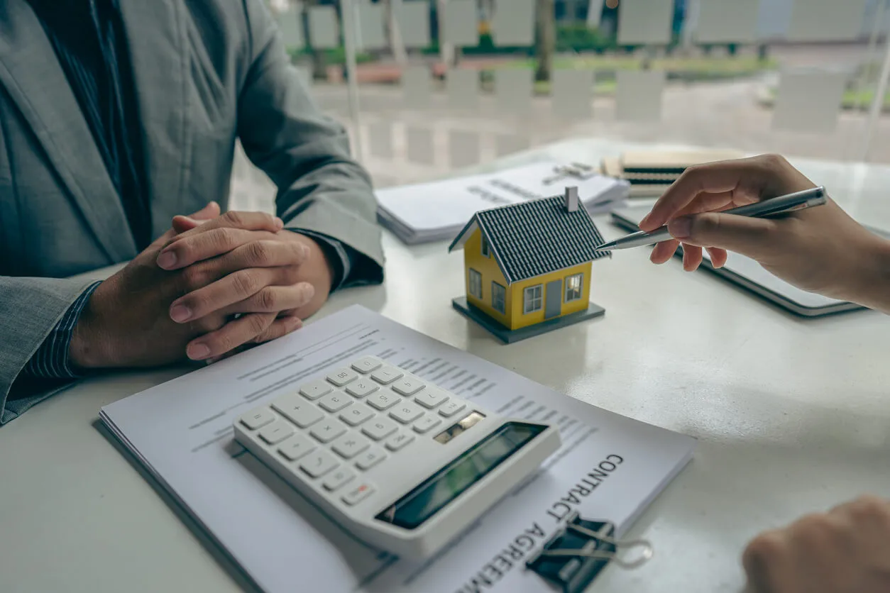 Deux personnes analysant un contrat de bail avec une calculette, illustrant la gestion locative à Rouen.