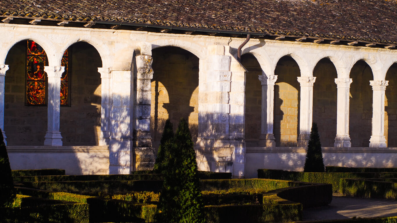 Cloître baigné de lumière à Marmande, avec ses vitraux colorés et son architecture ancienne, idéal pour promouvoir un investissement locatif Marmande