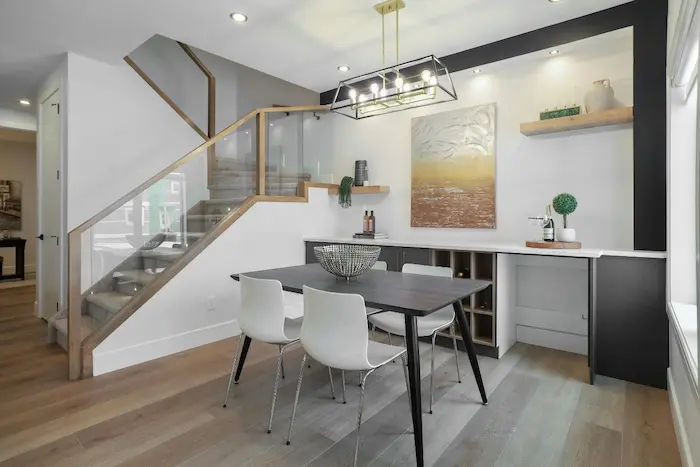 Salle à manger moderne avec table sombre et chaises blanches, image représentant une location meublée professionnelle pour un cadre élégant et fonctionnel.