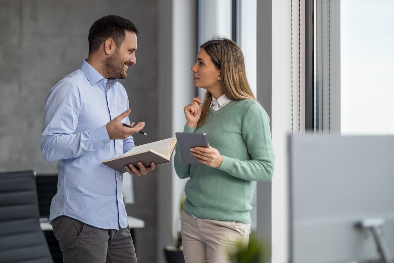 Deux personnes en discussion, expliquant comment calculer l’amortissement LMNP. L’une des personnes présente des documents ou un ordinateur, illustrant les étapes de calcul et les outils nécessaires pour optimiser la fiscalité en location meublée non professionnelle.