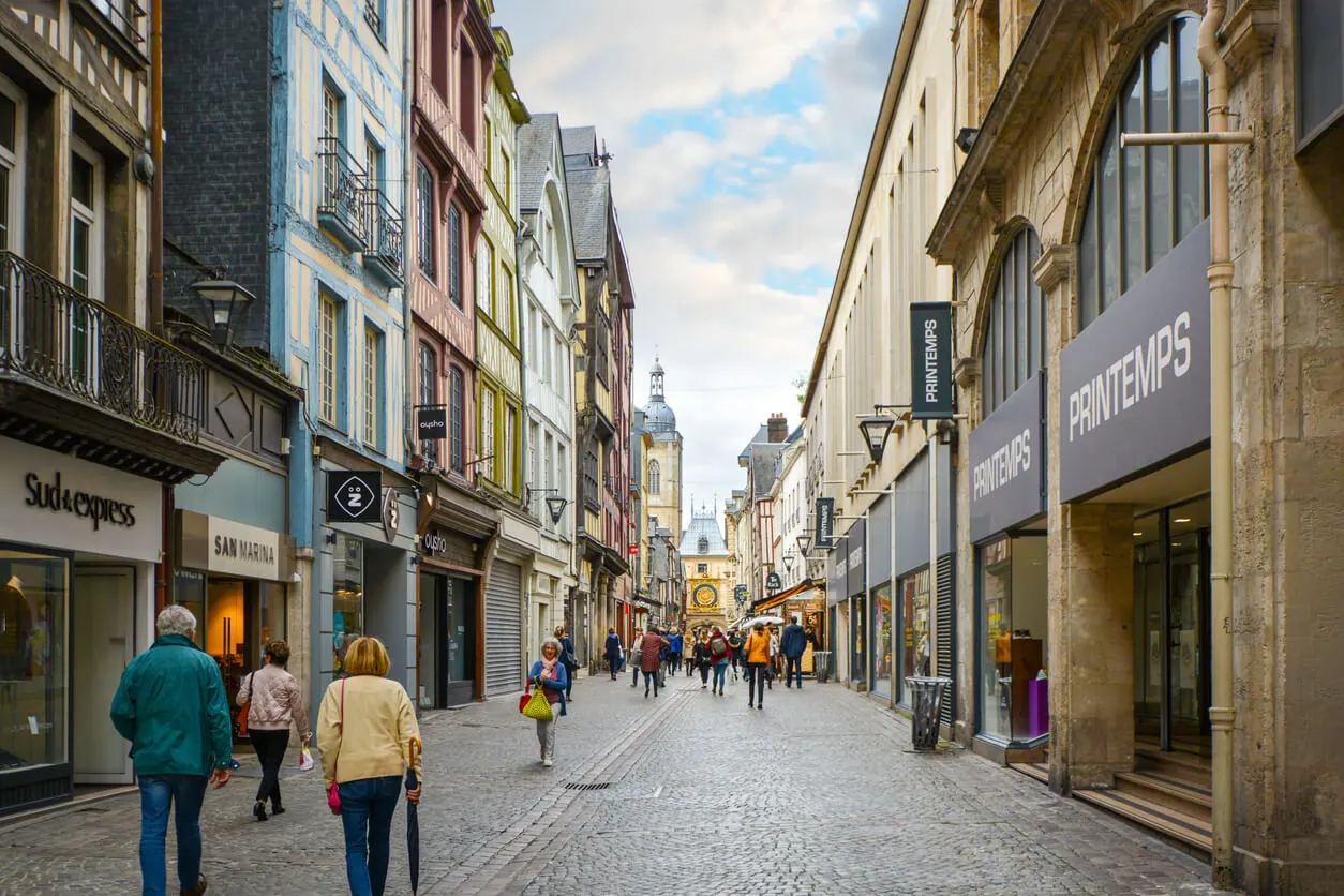 Vue d’un quartier animé de Rouen avec ses bâtiments typiques et ses commerces de proximité.