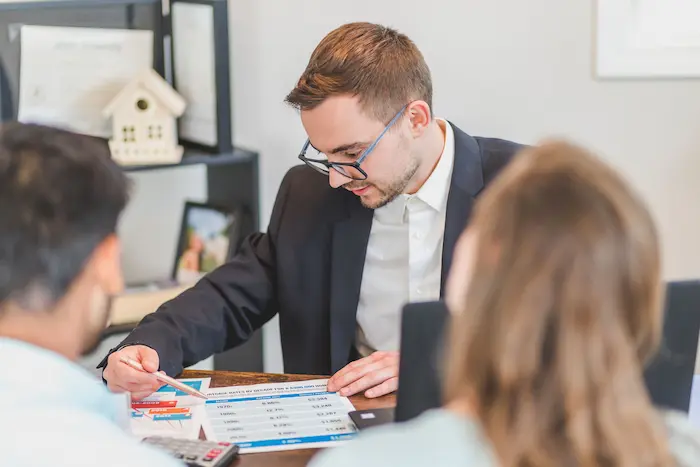 Trois personnes autour d’un bureau analysant graphiques financiers, reflet d’une stratégie utilisant l’effet de levier.