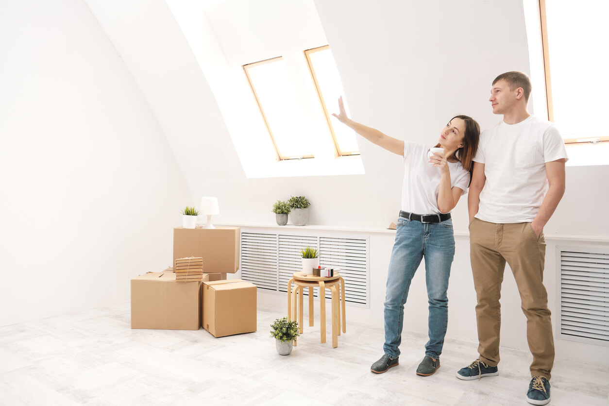 Un couple examine leur nouvel appartement lumineux, entouré de cartons. Une opportunité idéale pour démarrer l’investissement locatif Hérouville-Saint-Clair.