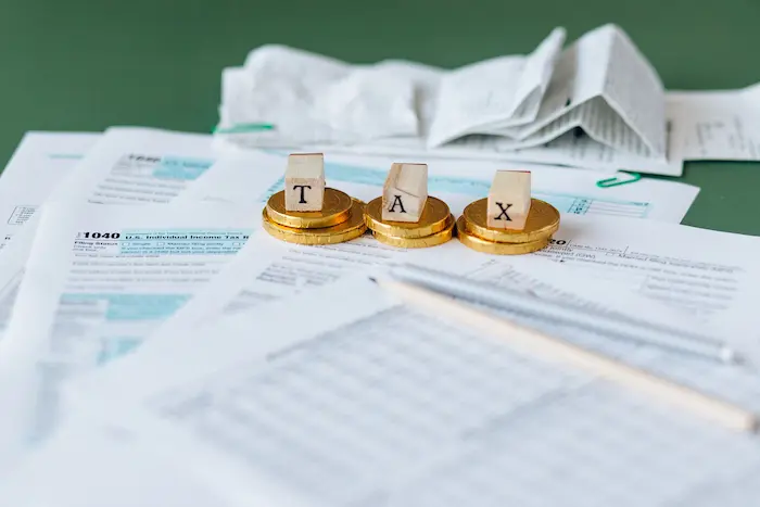 Formulaire fiscal américain posé sur bureau avec pièces et mot TAX en blocs, image qui illustre l’acte de déclarer son activité LMNP