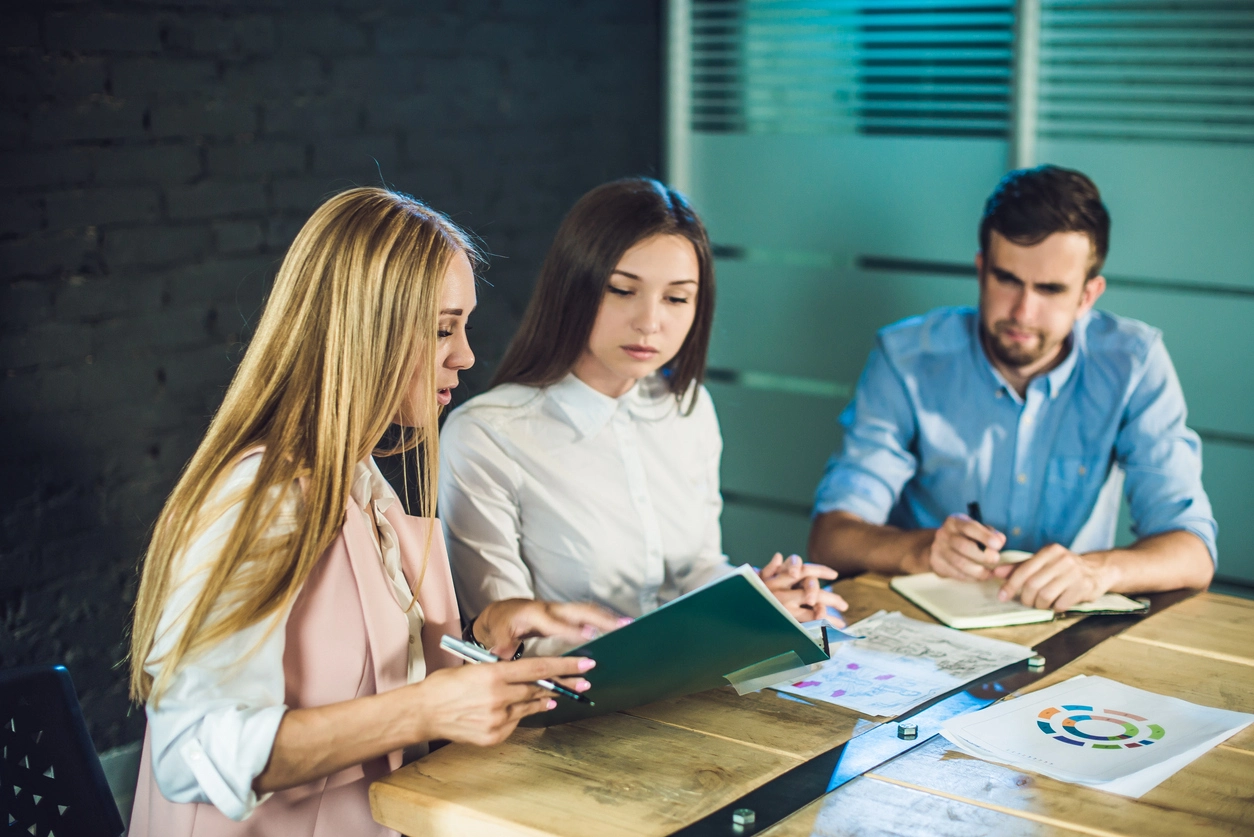 Trois personnes en réunion analysent des documents financiers liés au service de gestion locative.