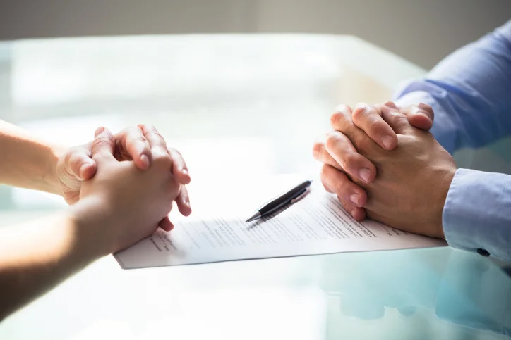 Deux hommes d'affaires entrain de discuter sur une table avec documents. Les frais résiliation mandat de gestion locative peuvent bien faire l'objet d'un accord à l'amiable.