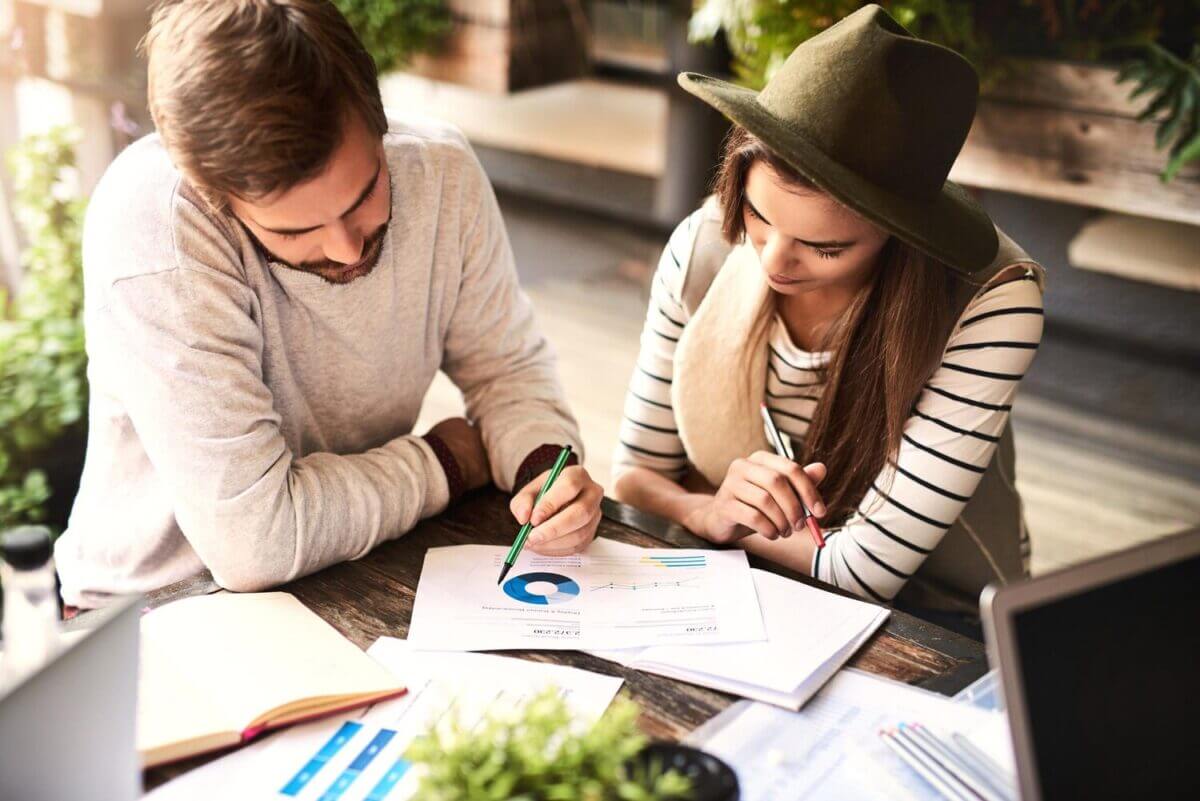 Deux personnes concentrées sur la gestion de la comptabilité, avec des documents financiers et un ordinateur portable. Illustration parfaite de la rigueur nécessaire pour la déclaration SCI 2024.