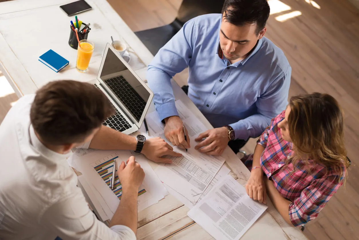 Un couple discute avec un conseiller bancaire, illustrant le processus de demande de prêt immobilier et l'importance de souscrire une assurance immobilier pour protéger leur projet.