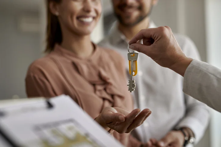 Deux couples qui sourient entrain de prendre les clés d'un responsable de gestion locative