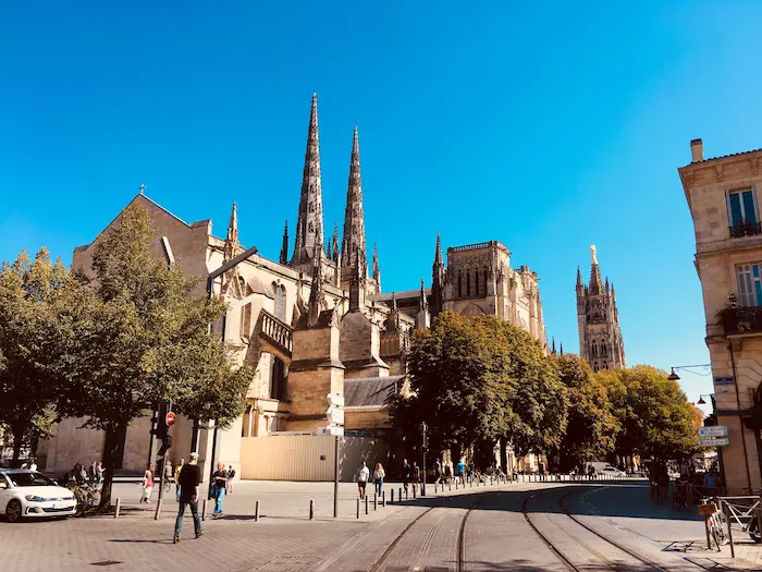 Cathédrale gothique majestueuse entourée de passants et tramway, reflet d’une ville attractive pour un investissement locatif réussi.