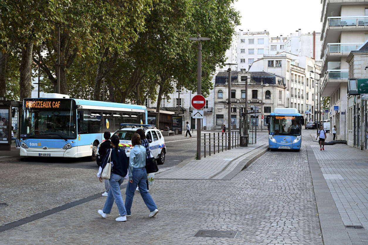 Scène urbaine à Niort avec des bus et des passants, illustrant la mobilité pratique, un atout pour un investissement locatif Niort attractif