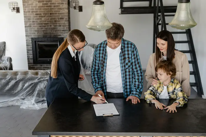Groupe réuni autour d’un document immobilier sur comptoir, image illustrant la signature d’un compromis de vente.