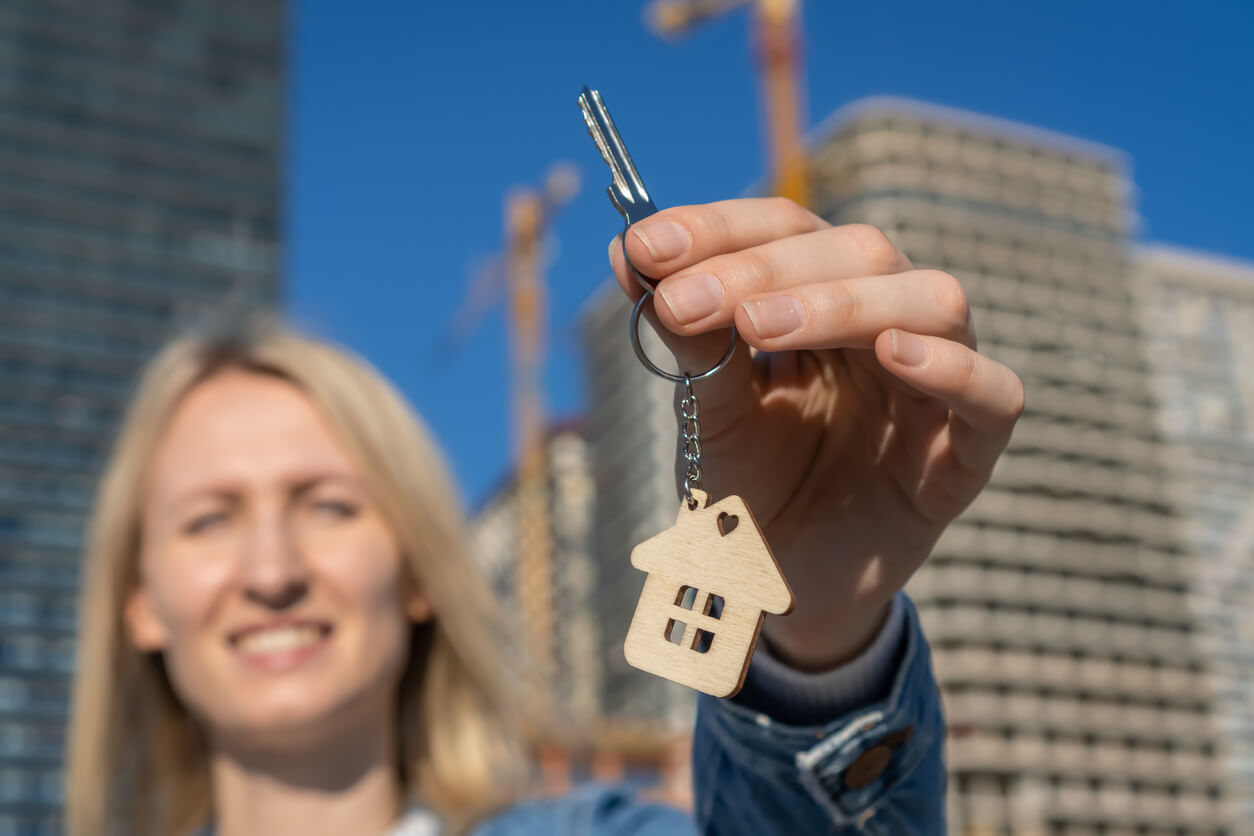 Une femme souriante vient d'investir dans un bien immobilier, optimisant ainsi sa fiscalité grâce à la défiscalisation immobilière pour réduire ses impôts tout en développant son patrimoine.