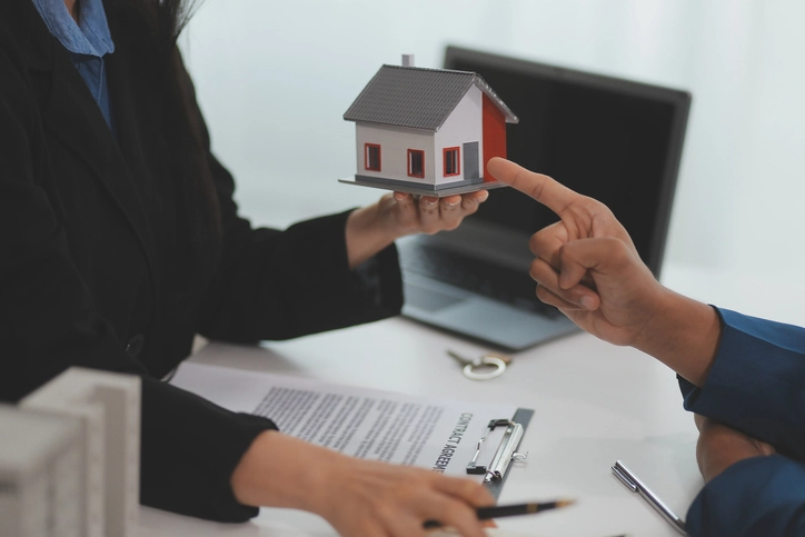 Deux personnes qui s'offrent une maquette de maison. L'efficacité de la gestion locative repose sur l'utilisation d'un outil innovant comme la gestion locative logiciel