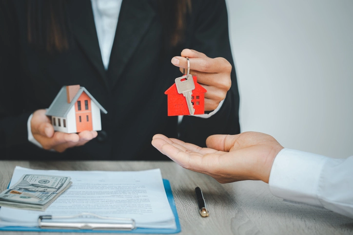 Une personne offrant à une autre une clé et un maison, qui témoigne de la confiance que les bailleurs ont envers les chargés de gestion locative.