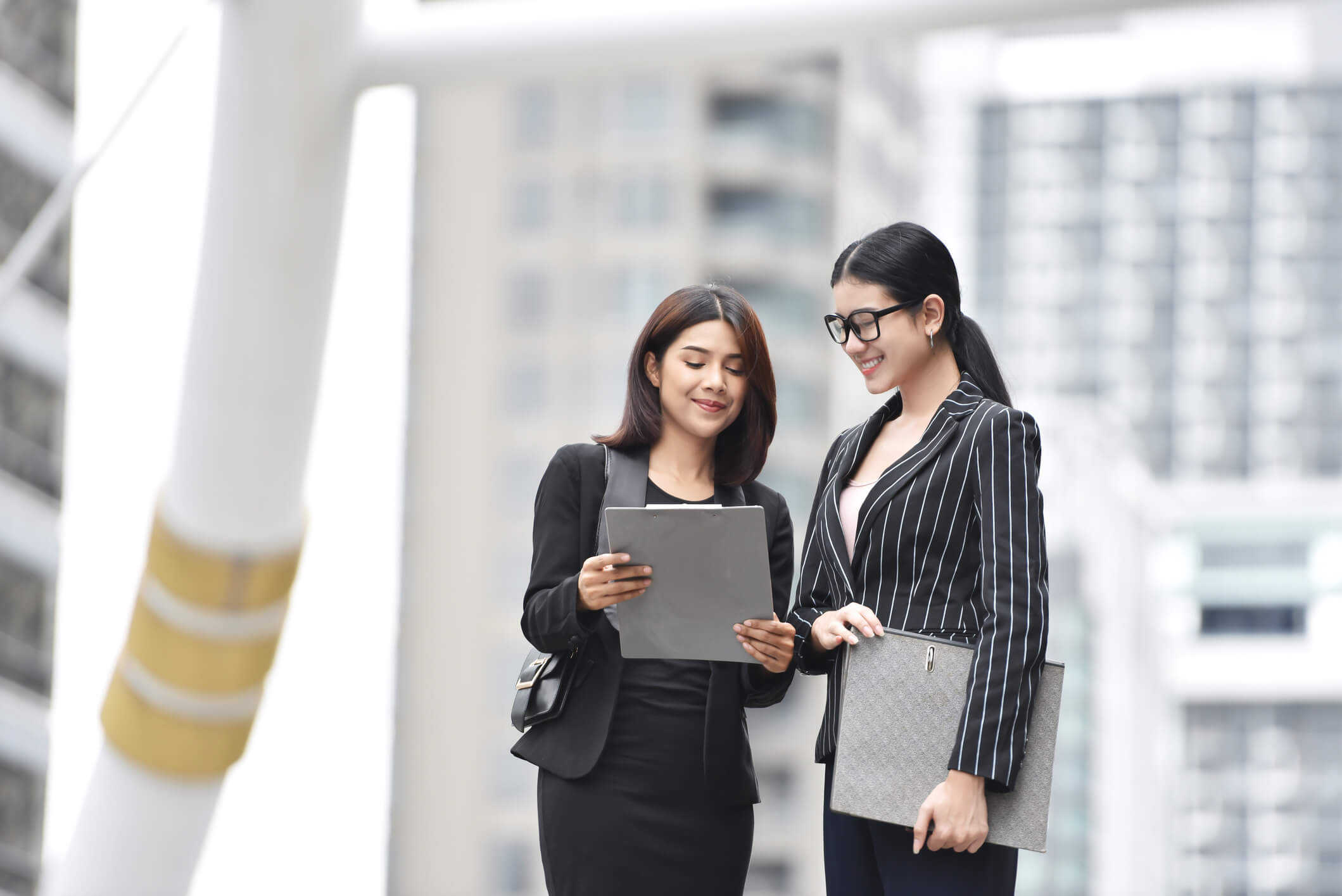 Deux femmes discutent des stratégies pour réduire la fiscalité liée à la cession de parts de SCI, analysant des options fiscales dans un cadre professionnel.